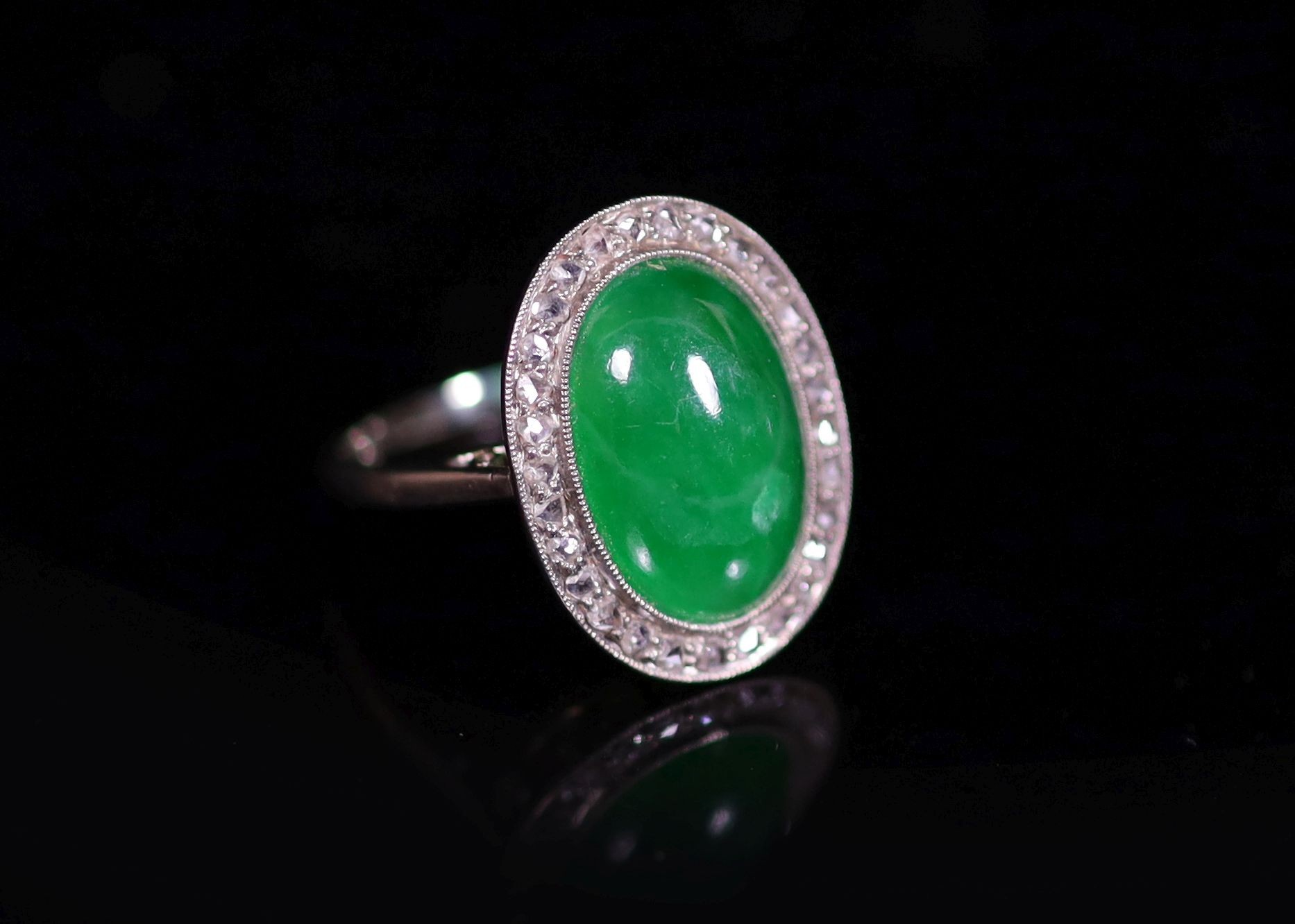 A 1920's 18ct white gold, oval cabochon jadeite and rose cut diamond millegrain set dress ring